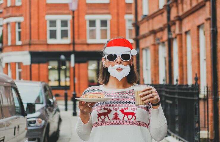 Donna con maglione natalizio e maschera di Babbo Natale